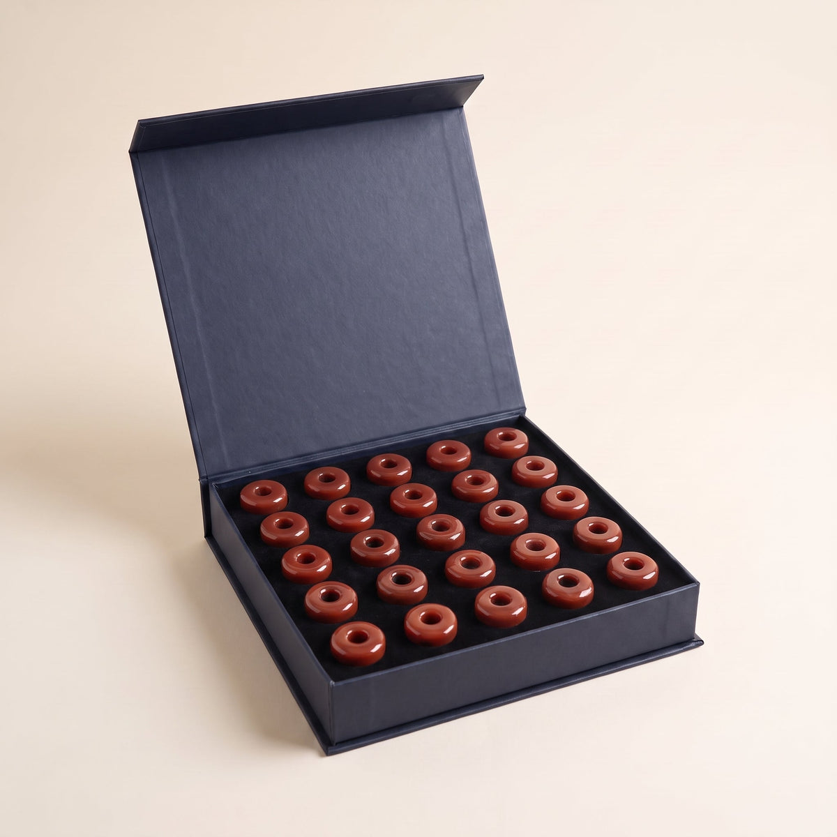 علبة غَزل مفتوحة — قطع مستكة حمراء لامعة على شكل دونات داخل الـ tray