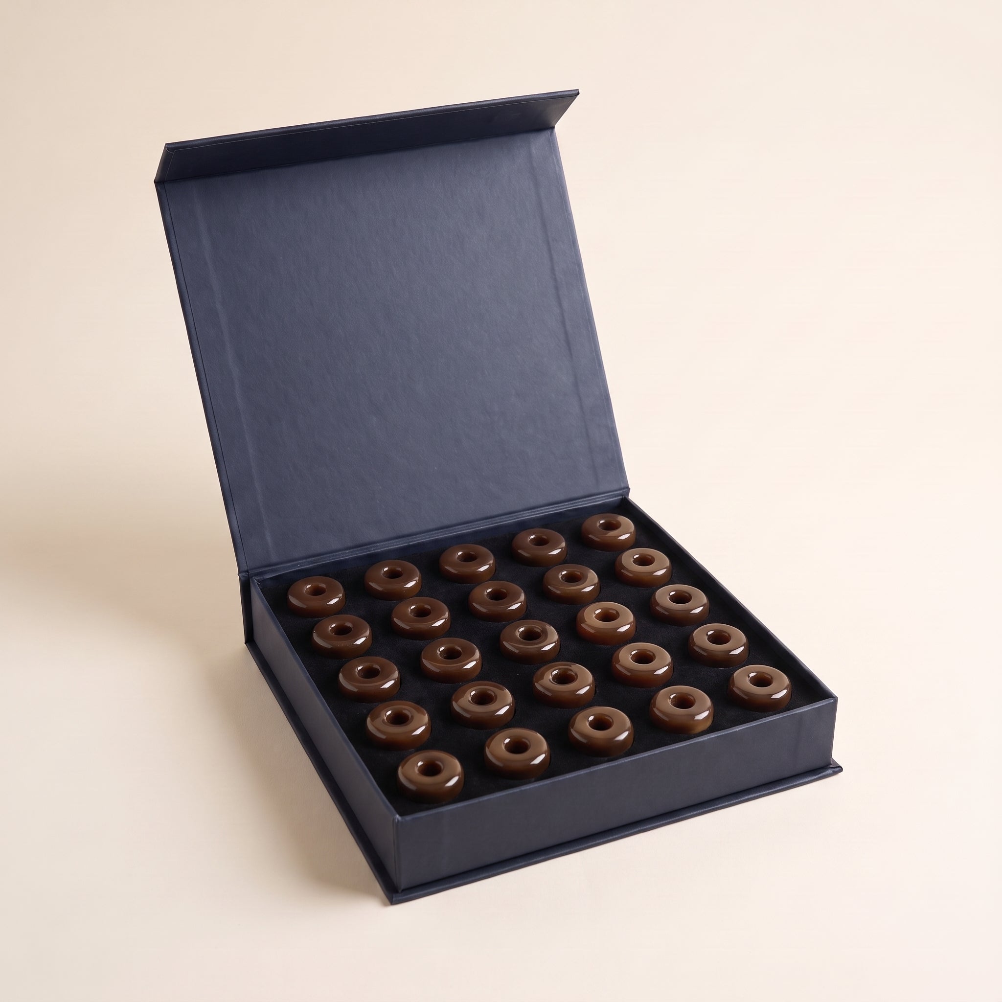 علبة وقار مفتوحة — قطع مستكة بنية لامعة على شكل دونات